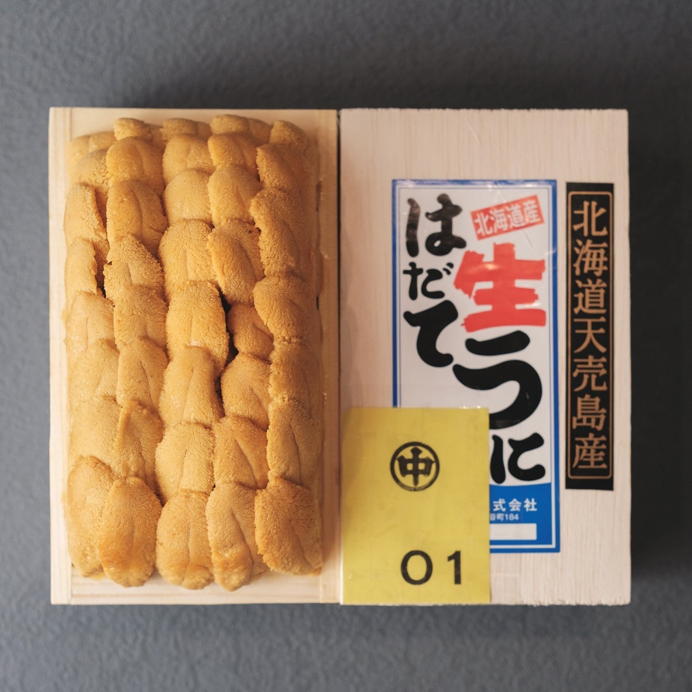 Taka’s Sushi 分享的金色海胆,盛于木盒中,旁边摆着盒盖与黄色01标签