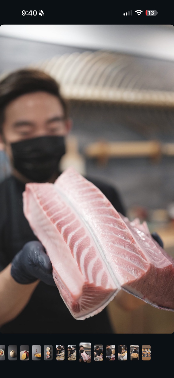 Taka’s 厨师在寿司吧台手持两块油花丰润的金枪鱼肉