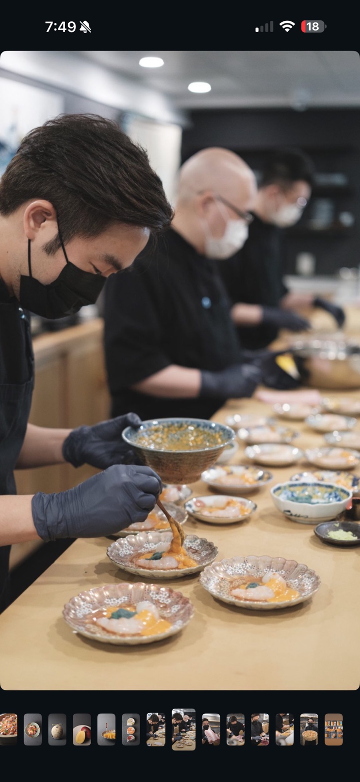 厨房员工在寿司吧台后,细心准备分装于小盘的料理