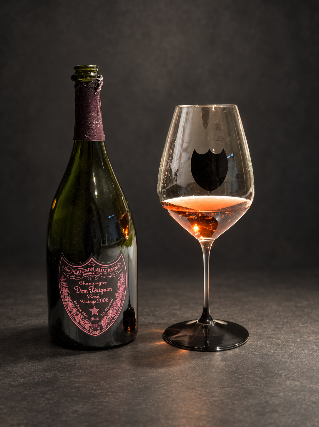 Dom Pérignon Rosé 2006年份香槟酒瓶与一杯桃红香槟,置于炭灰色背景前