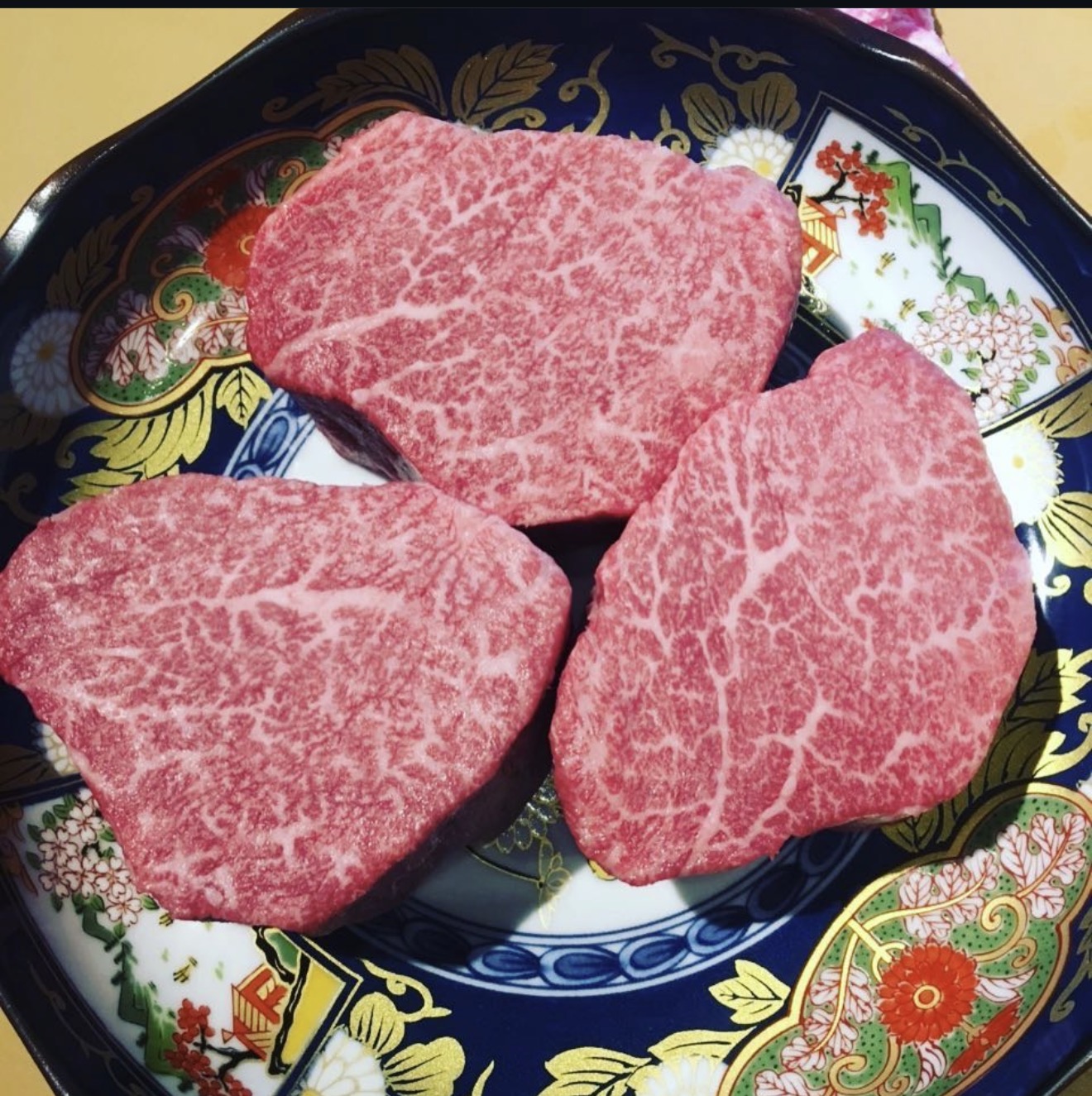 三块油花细腻的宫崎 A5 和牛,摆放在带有花纹的陶瓷盘上