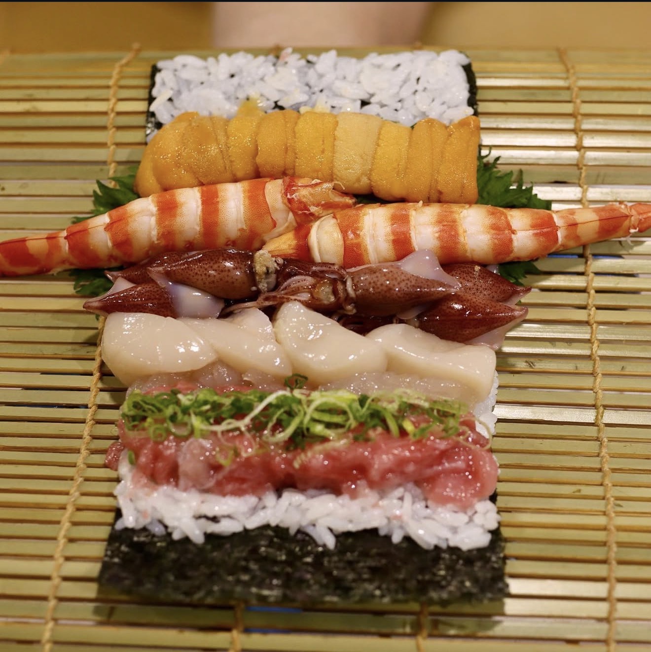 Taka’s 正在制作时令特选大卷，将海鲜铺在米饭与海苔上