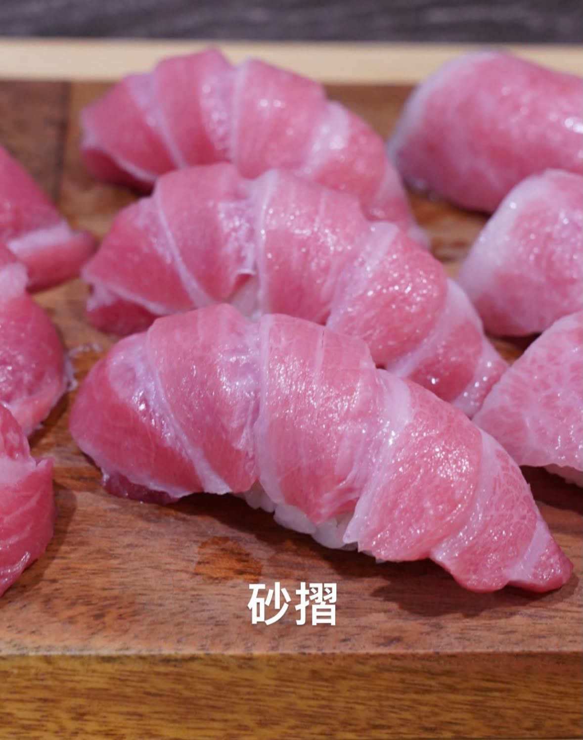 木质餐板上排列的蓝鳍金枪鱼大腹握寿司，鱼片切工细致，油脂纹理丰富